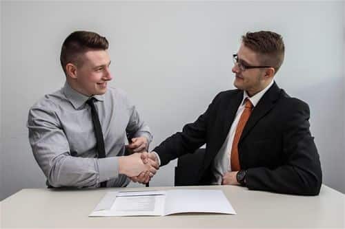 Dois homens de camisas sociais cumprimentando-se após fechar parceria 